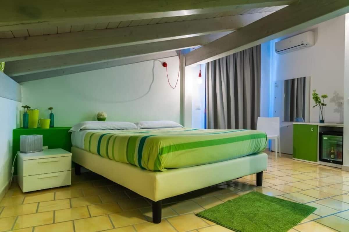 A bedroom with a bed, a nightstand, a green cabinet, and a window with curtains.