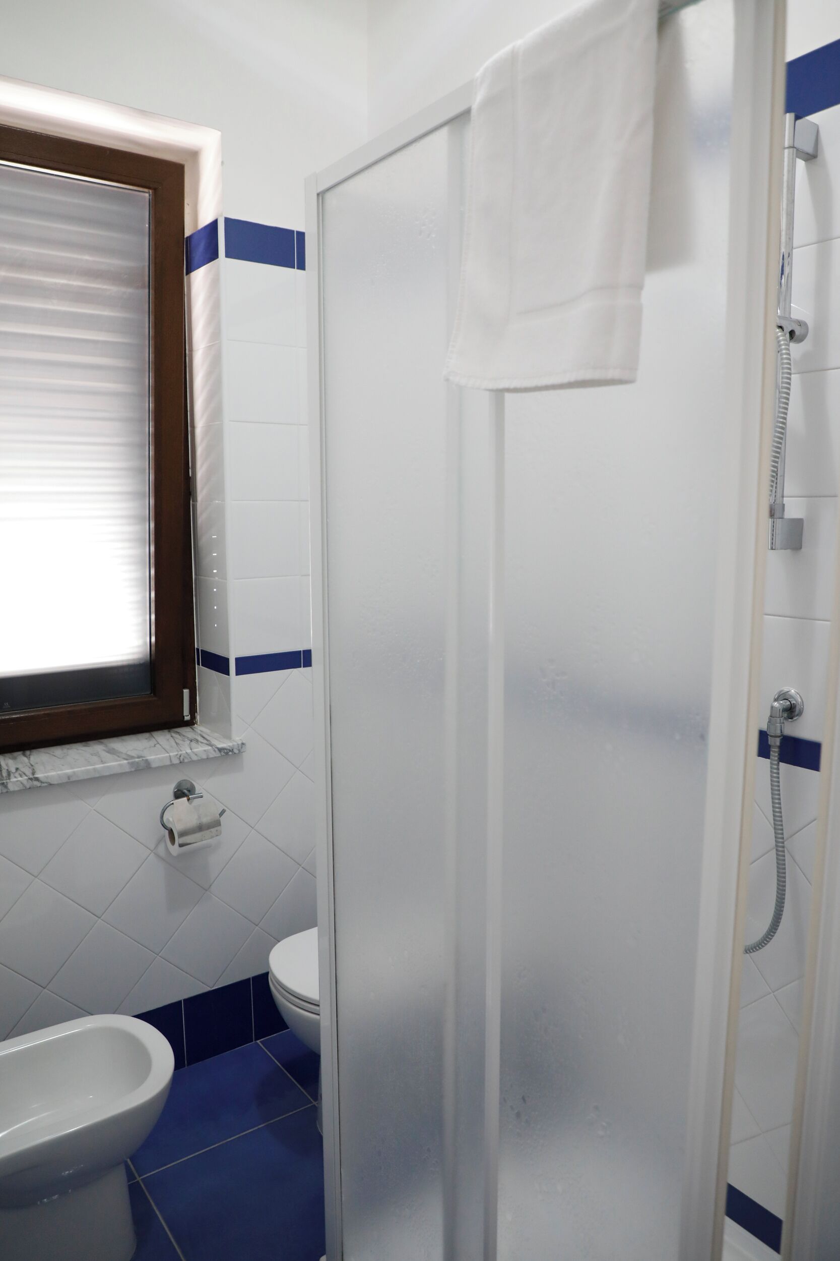 Un bagno con box doccia in vetro, un water e un bidet.