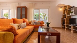 A living room with a sofa, a coffee table, and a TV on a brick wall. - Vacation home Dani by Interhome (L'Ampolla)