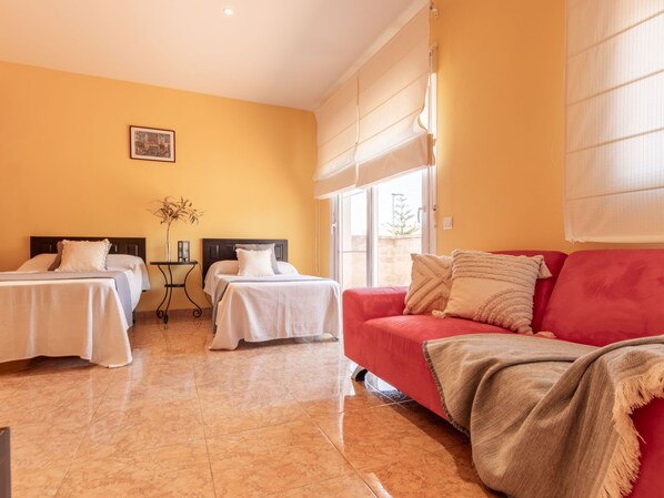 Habitación de hotel con dos camas, un sofá rojo y un ventanal grande.