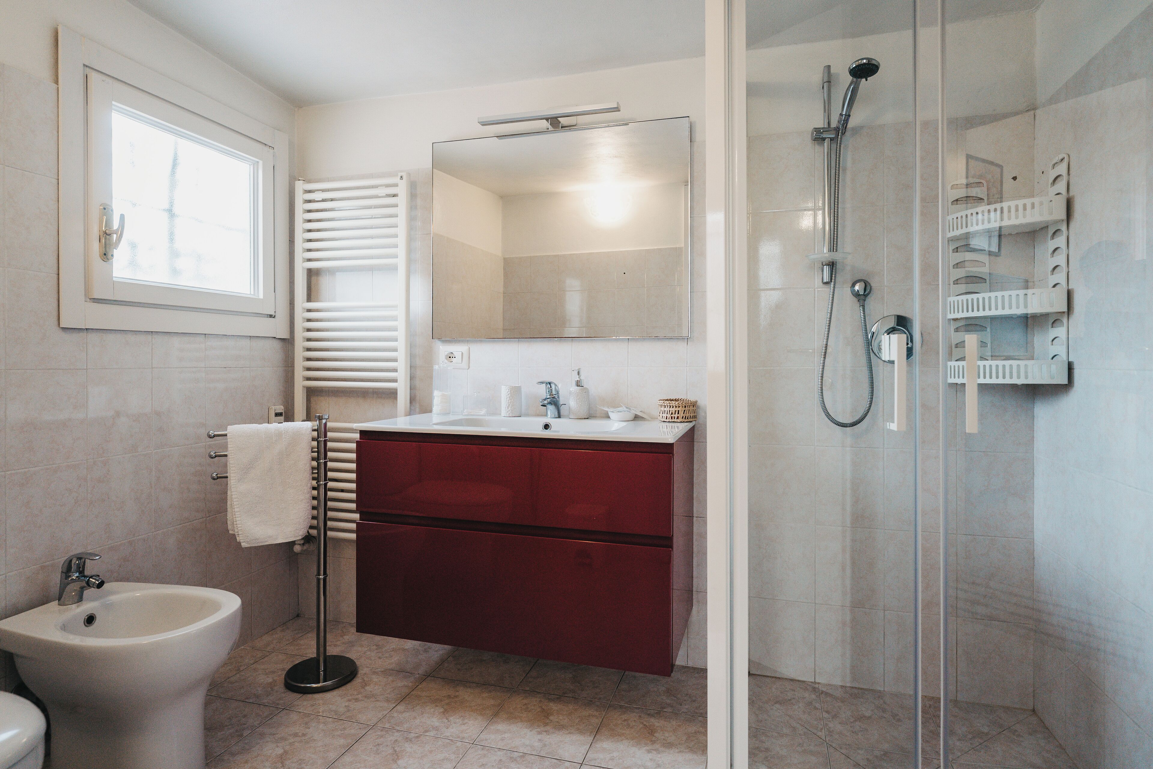 A modern bathroom with a bidet, a sink, a mirror, and a glass-enclosed shower.
