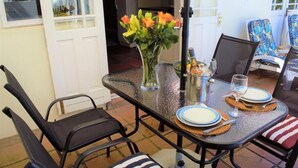 A dining table set with plates, glasses, and a vase of flowers. - Quaint family home close to Tram terminal (Franschhoek)