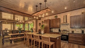 Eine geräumige Küche mit Holzausstattung, einer Marmorarbeitsplatte und einer großen Kochinsel mit Barhocker.