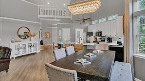 A spacious dining area with a large table, multiple chairs, and a chandelier. - Unique 3BR condo plus *LOFT* w/ golf cart & spacious open floor plan at Sandestin Golf & Beach Resort! (Miramar Beach)