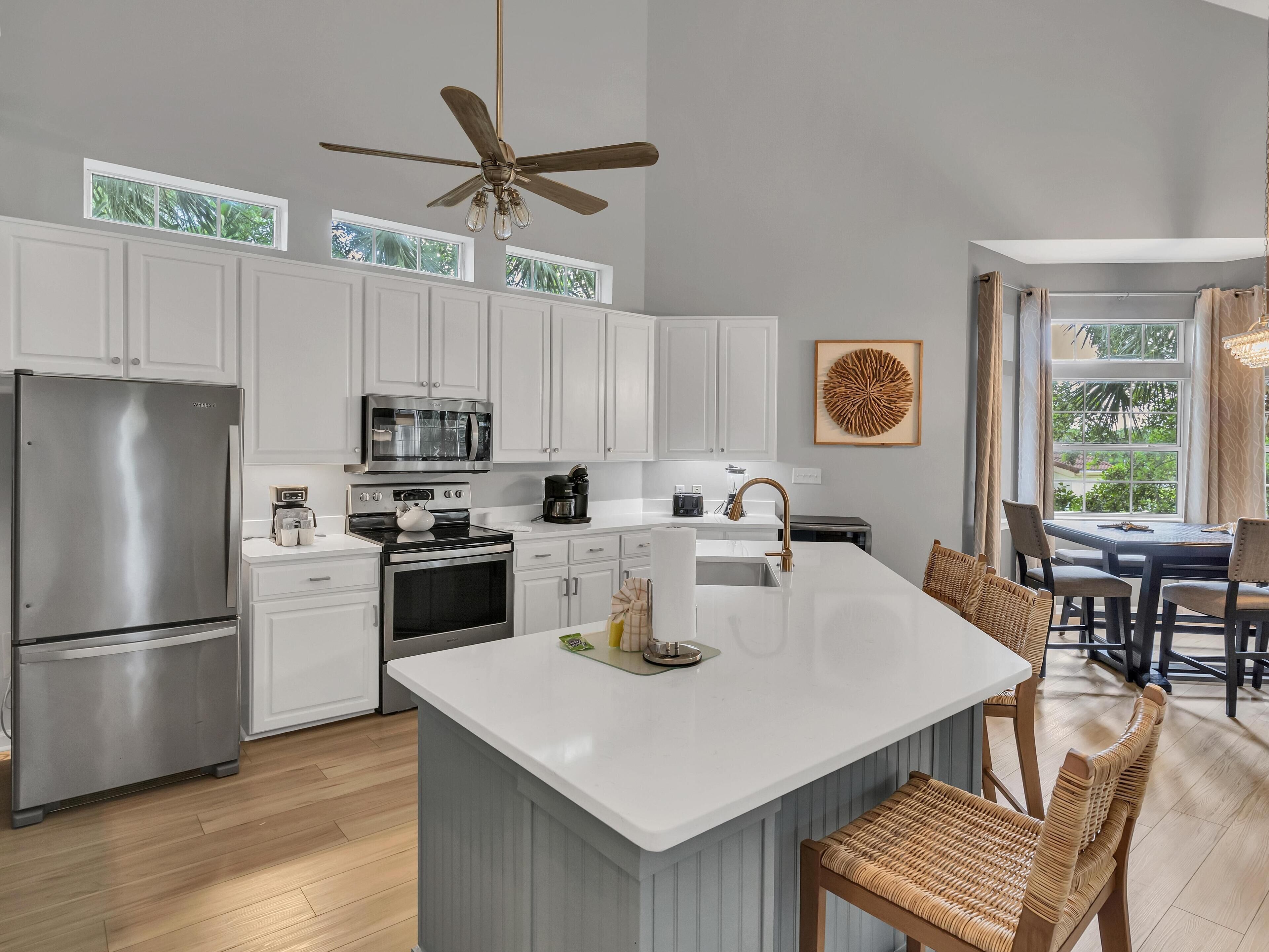 A modern kitchen with white cabinetry, stainless steel appliances, and a large island with seating.