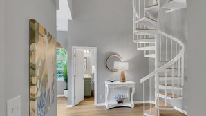 A modern interior with a spiral staircase, a hallway leading to a bathroom, and a painting on the wall. - Unique 3BR condo plus *LOFT* w/ golf cart & spacious open floor plan at Sandestin Golf & Beach Resort! (Miramar Beach)