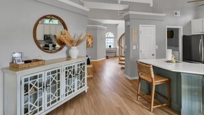 A spacious kitchen with wooden flooring, a white console table, and a large mirror. - Unique 3BR condo plus *LOFT* w/ golf cart & spacious open floor plan at Sandestin Golf & Beach Resort! (Miramar Beach)