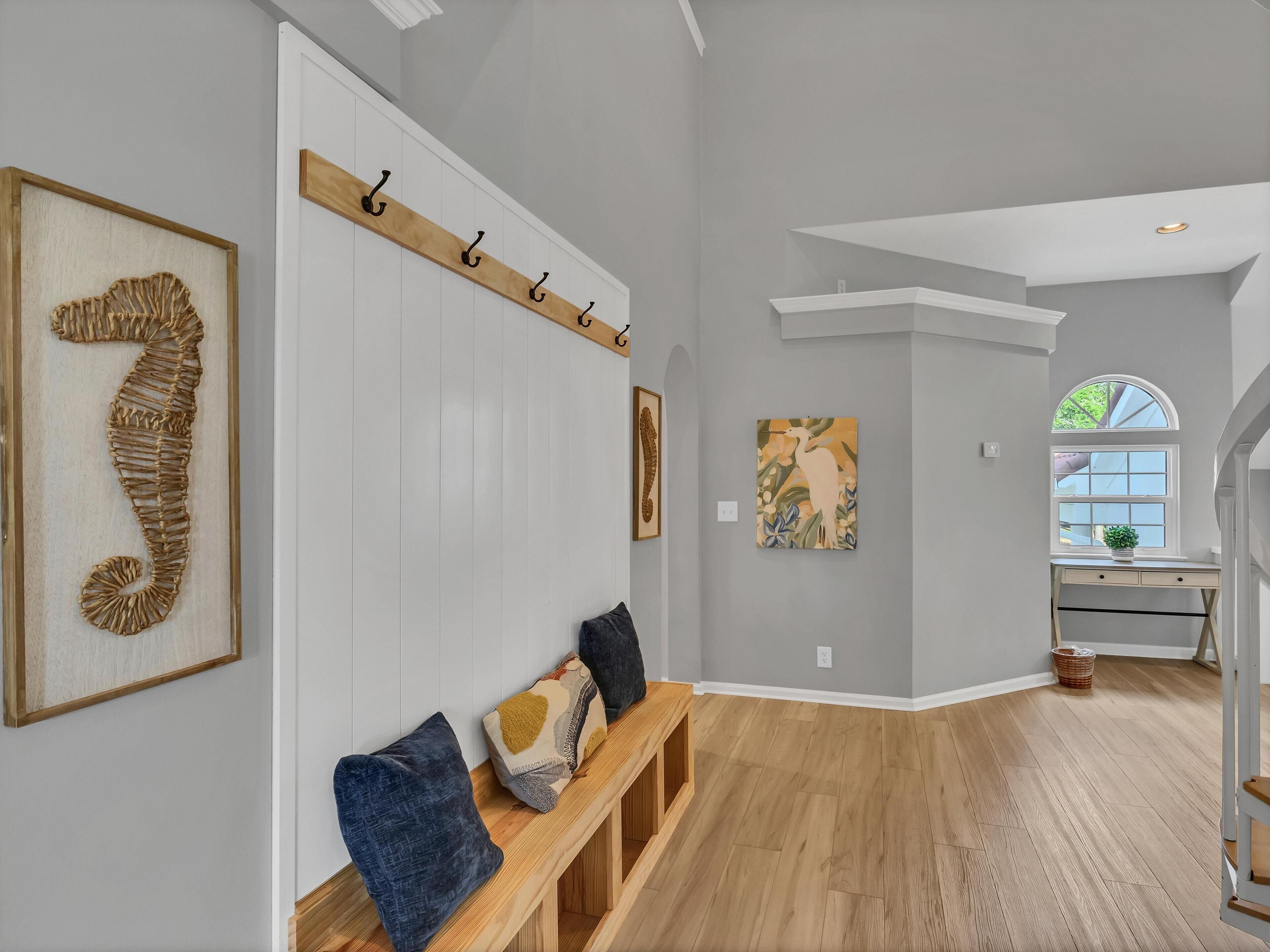 A spacious hallway with a wooden bench, a coat rack, and artwork on the walls.