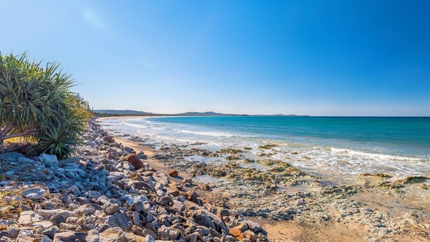 A rocky beach with clear blue waters and distant hills. - Hibiscus Dreaming - Brooms Head Village Location (Brooms Head)