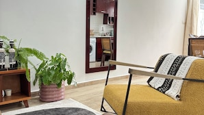 Un salon avec un canapé, un fauteuil, une plante en pot et un tapis.