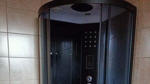 Un ascensor con paredes de vidrio, panel de control y botón de emergencia.