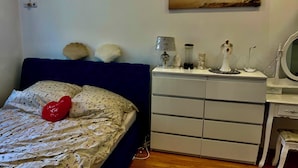Un dormitorio con cama, cómoda, espejo y un cuadro en la pared.