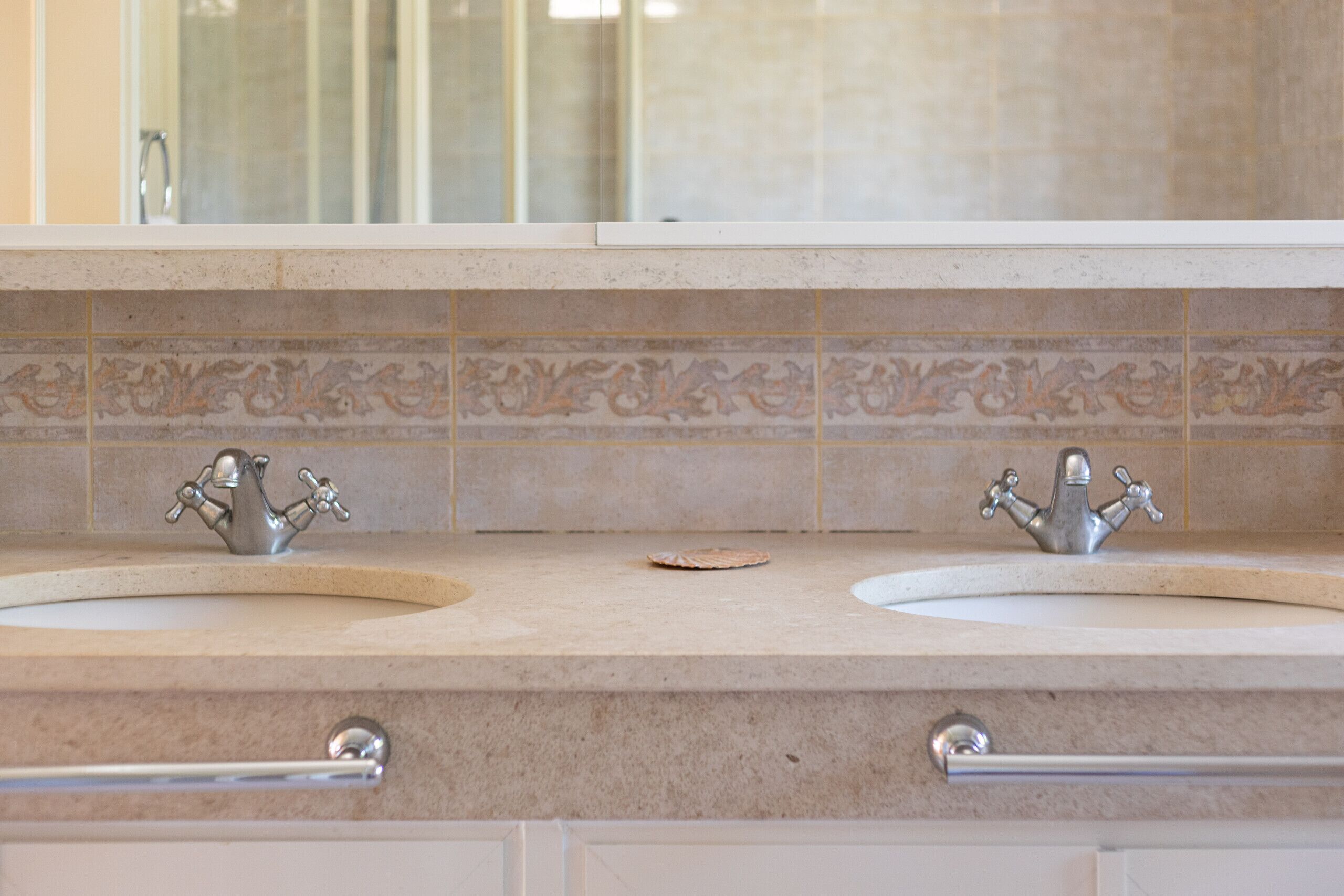 A bathroom with two sinks, a mirror, and decorative tiles.