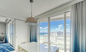 A hotel room with a large window, a dining table, and a hanging light fixture. - LVS W FTL 1409 - Beachfront Resort Condo | 2 Bed / 2 Bath with Southeast Ocean View (Fort Lauderdale)