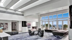 A spacious living area with a large window, a seating arrangement, and a view of the ocean.
