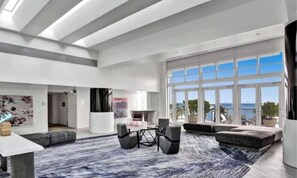 A spacious living area with a large window, a seating arrangement, and a view of the ocean.