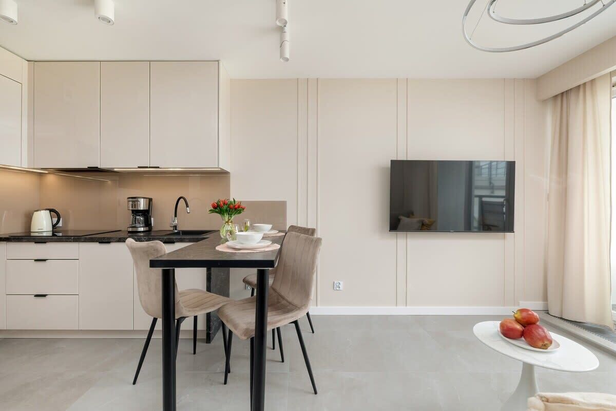 Een moderne keuken met een eethoek, een flatscreen televisie aan de muur en een kleine tafel met fruit.