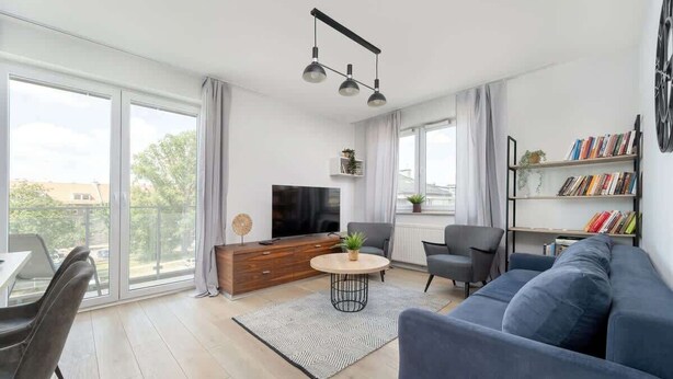 Una sala de estar moderna con sofá, televisor y estantería.