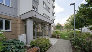 Un edificio moderno con entrada de vidrio, un sendero pavimentado y un banco.