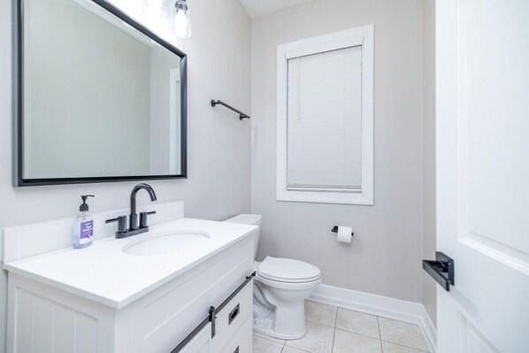 Un baño moderno con un lavabo blanco, un espejo grande y un inodoro.