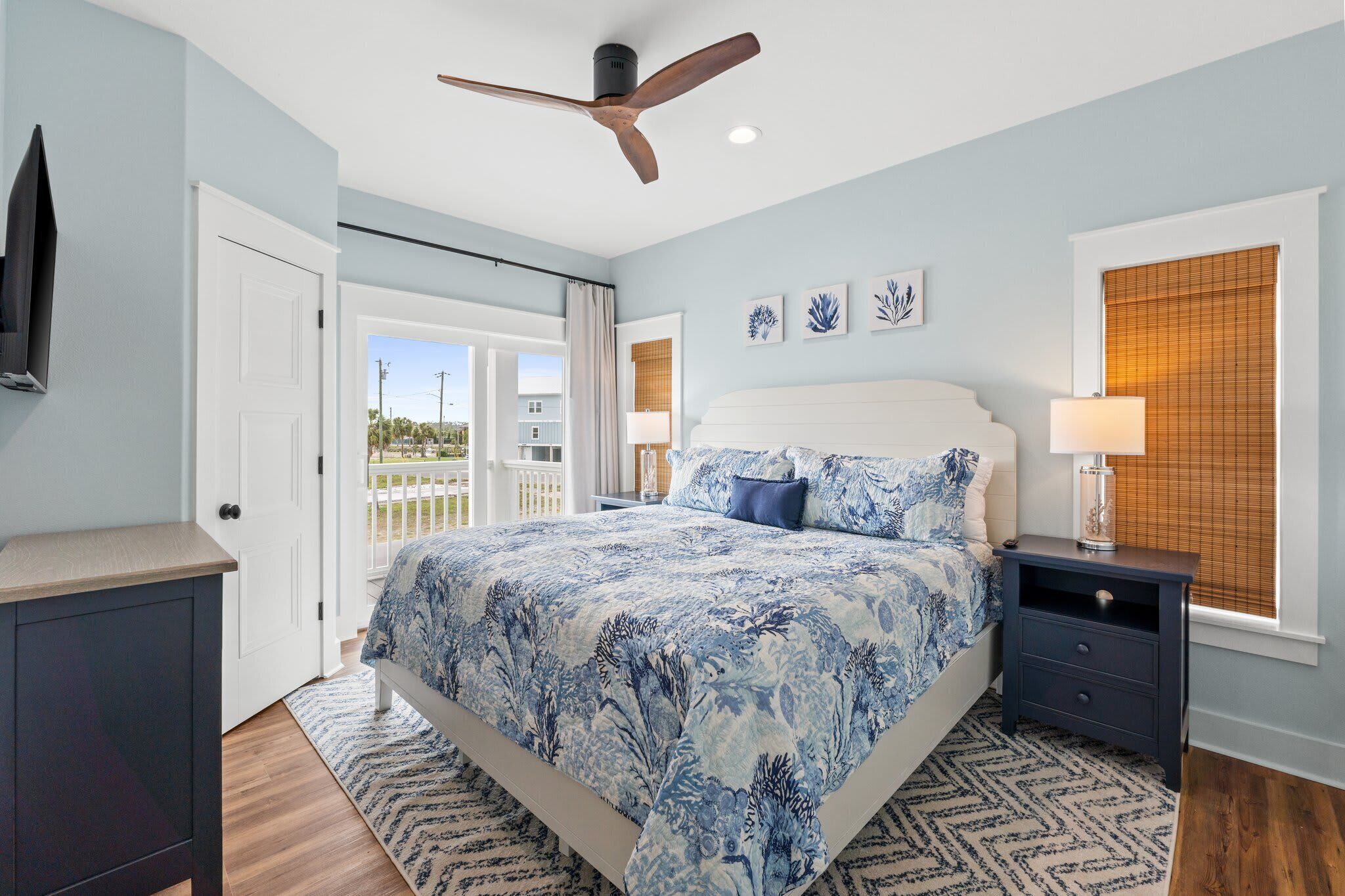 A bedroom with a bed, a ceiling fan, a nightstand, a TV, and a window with blinds.