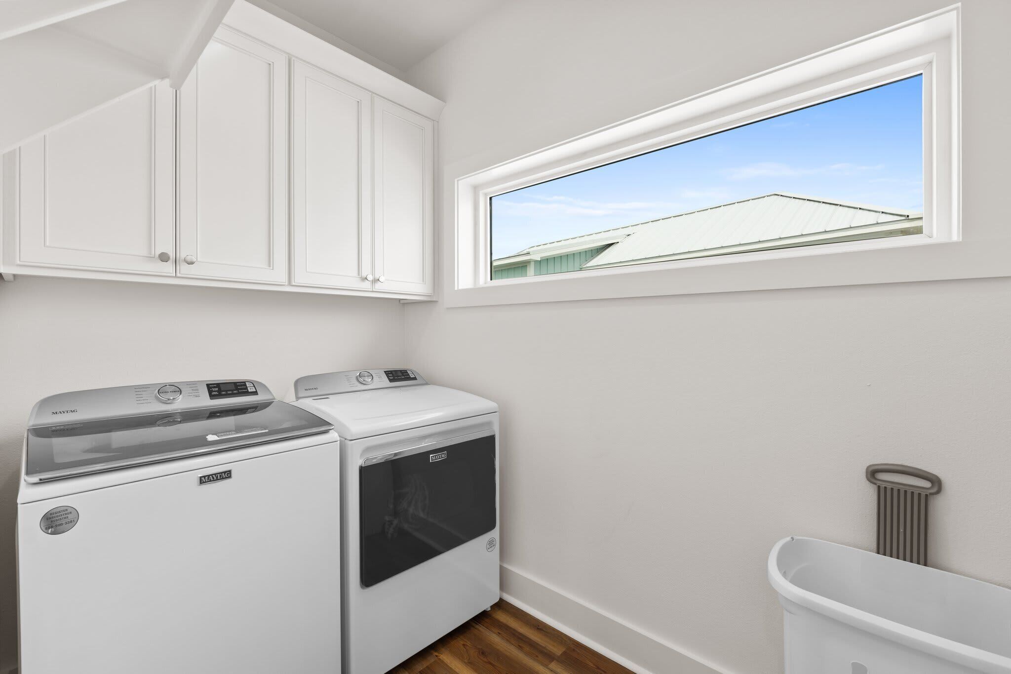 A laundry room with a washing machine, dryer, and a window with a view of a building.