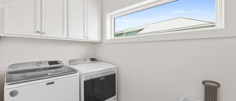 A laundry room with a washing machine, dryer, and a window with a view of a building.