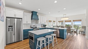 A modern kitchen with a central island, stainless steel appliances, and a view to the outdoors. - Twist of Lime - Mexico Beach, Unobstructed Gulf view, Elevator, Private Pool, Tw (Mexico Beach)