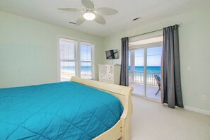 Ein Schlafzimmer mit Bett, Deckenventilator, Fernseher und Blick auf den Strand.