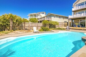 A backyard with a swimming pool, a wooden deck, and a two-story house with a balcony.