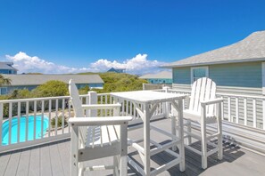 En terrasse med pool, hvide møbler og udsigt til huse i baggrunden.