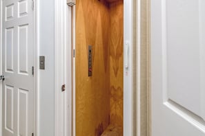Un interior de madera con una puerta, un panel de control en la pared y un marco blanco.