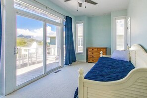 Un dormitorio con cama, cómoda y vistas al exterior a través de una puerta corrediza de vidrio.
