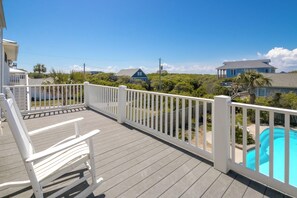 A wooden deck with white railings, a pool, and a view of neighboring houses. - Sea Dragon - 6BR, Great Ocean Views, Pool, Hot Tub, Dog Friendly! (Surf City)