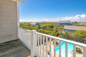 Uma varanda com vista para uma área residencial, uma piscina e casas ao fundo.