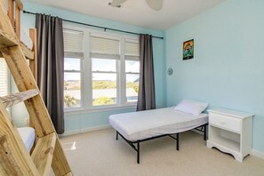 Quarto com cama, mesa de cabeceira, janela com cortinas e vista para o exterior.