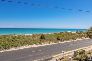 Uma estrada costeira com vista ampla para o oceano e uma praia arenosa.