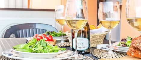Una mesa servida con una botella de vino, dos copas, un plato de ensalada y una tabla de madera.