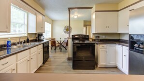 A kitchen with white cabinets, a black stove, and a refrigerator. - Indoor fireplace with patio and pool table (Beaumont)