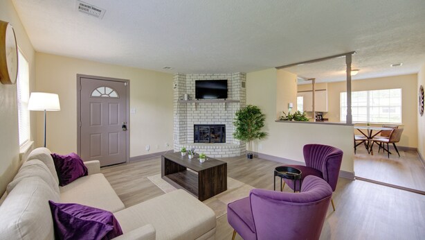 A living room with a fireplace, a sofa, a coffee table, and a television. - Indoor fireplace with patio and pool table (Beaumont)