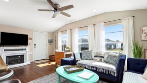 A living room with a fireplace, a sofa, a coffee table, and a television. - Welcome to Blue Jewel! (Galveston)
