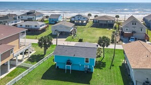 A coastal residential area with houses, a blue house in the foreground, and a view of the ocean. - Welcome to Blue Jewel! (Galveston)