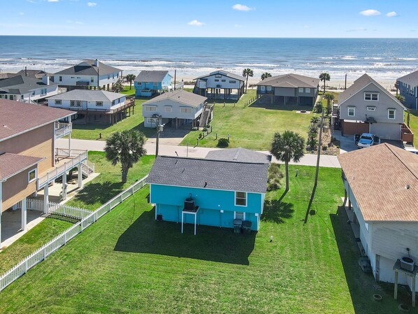 A coastal residential area with houses, a blue house in the foreground, and a view of the ocean. - Welcome to Blue Jewel! (Galveston)
