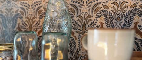 A table with a glass bottle, a glass jar, and a white mug.