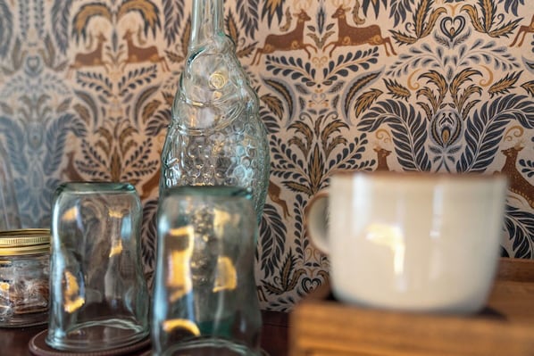 A table with a glass bottle, a glass jar, and a white mug. - The Buddle Inn (Ventnor)
