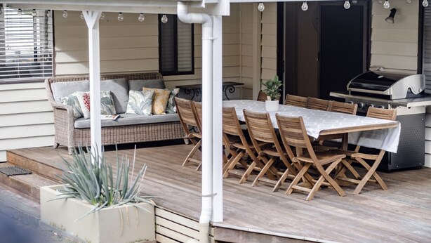 A covered patio with a dining table and chairs, a grill, and a sofa with cushions. - Sandy Cottage in Narrawallee (Narrawallee)