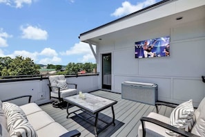 Une terrasse sur le toit, dotée d’un espace extérieur aménagé avec des sièges, d’un écran de télévision et offrant une vue sur le paysage.