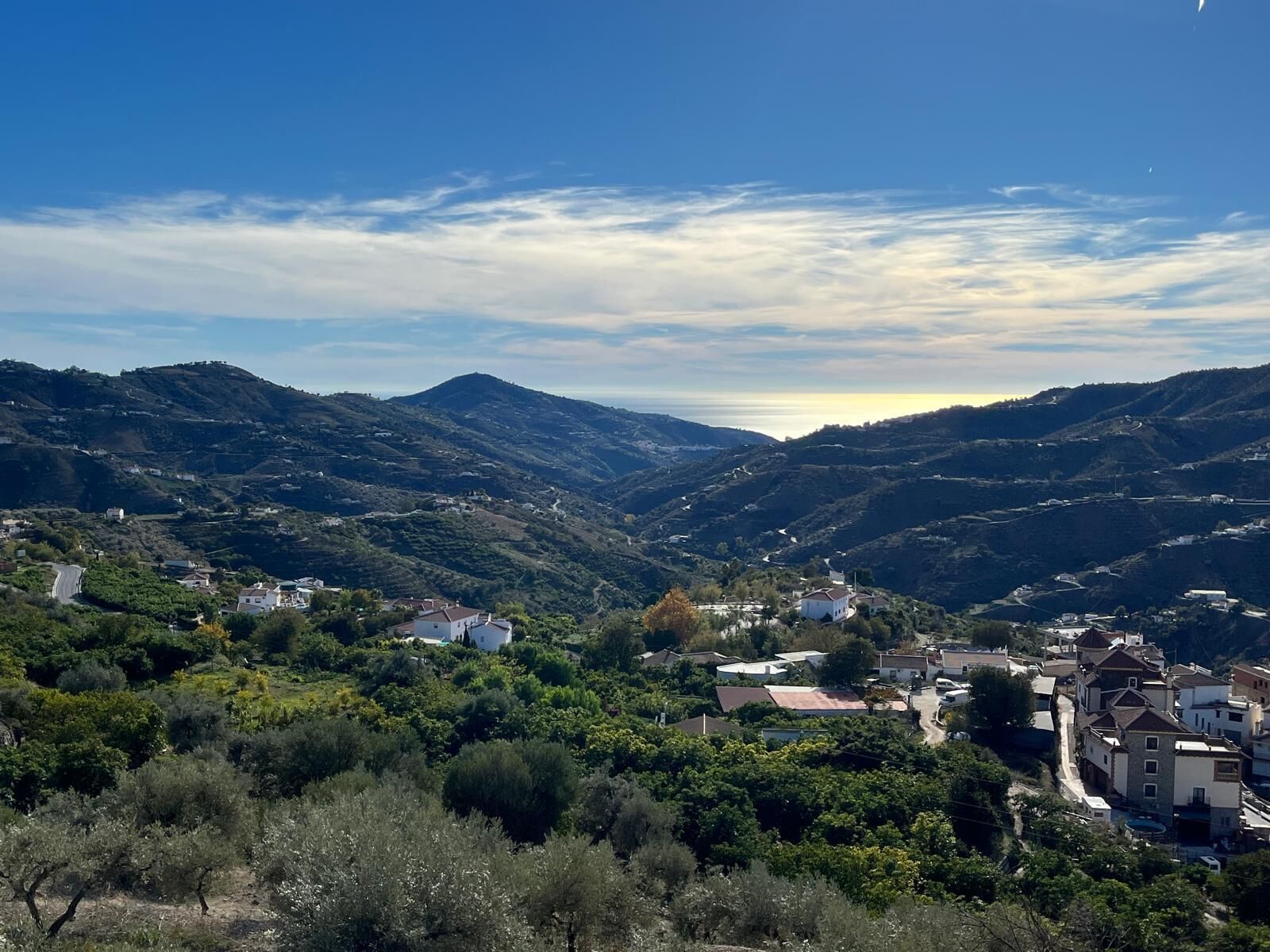 Un paysage montagneux avec une vallée et quelques bâtiments dispersés.