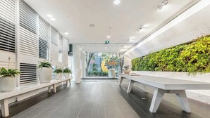 Una hall moderna con una panca, una reception e una parete verde.