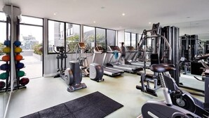 Ein modernes Fitnessstudio mit Laufbändern, Kraftgeräten und einem Rudergerät.